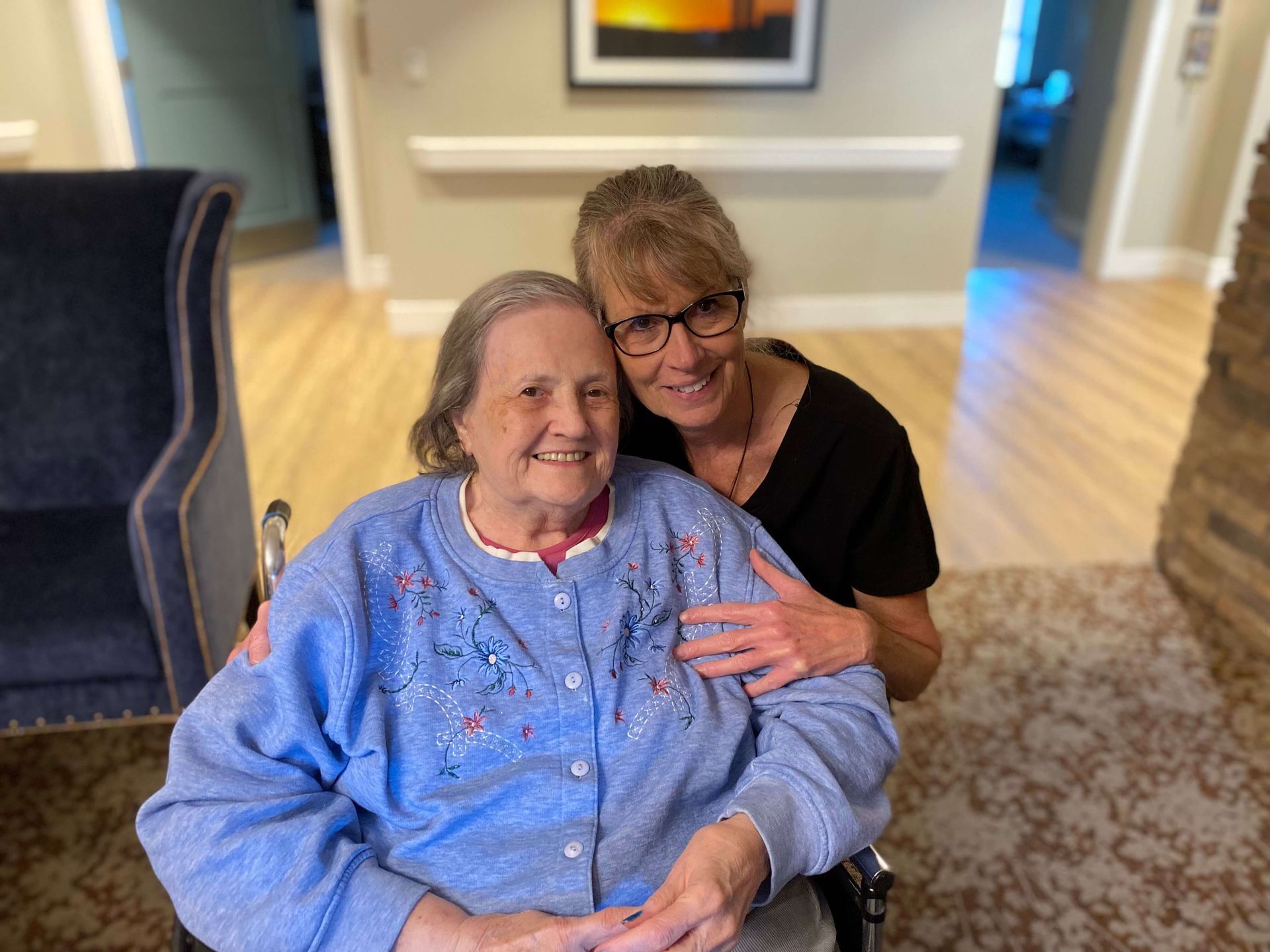 nursing home caregiver giving a side hug to a resident
