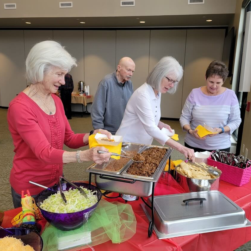 senior residents dishing up tacos at the Cinco de Mayo party