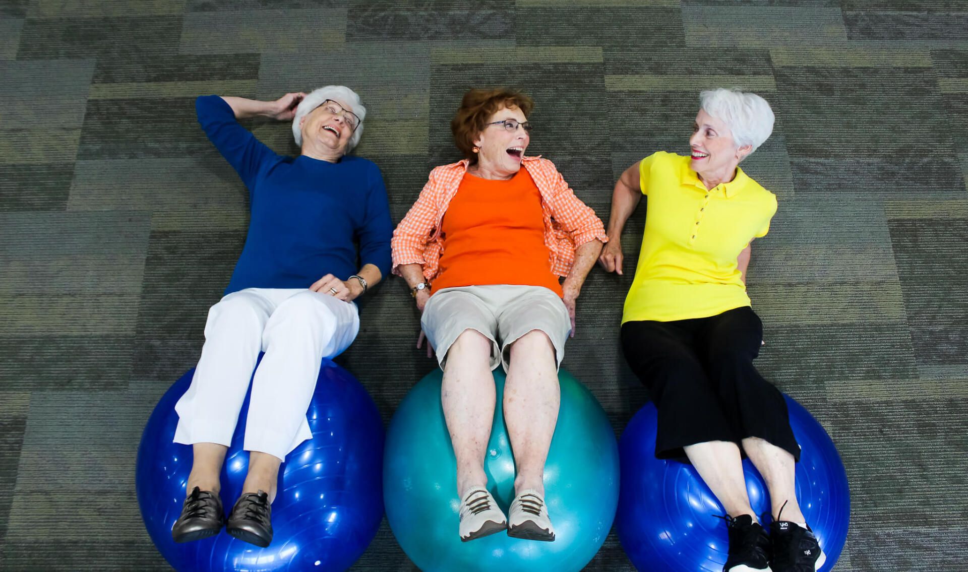 Retired ladies participating in the wellness program by exercising their legs with exercise balls