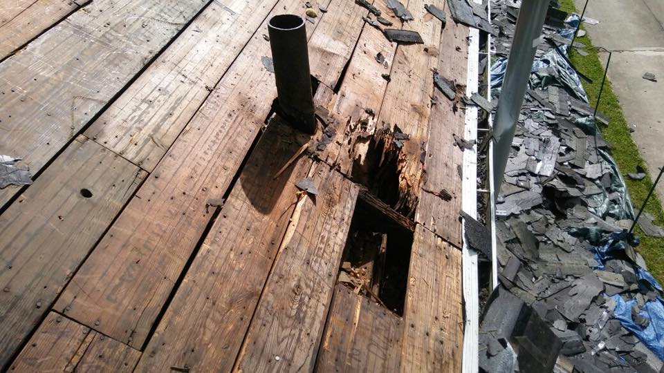 A hole in a wooden deck with a pipe coming out of it