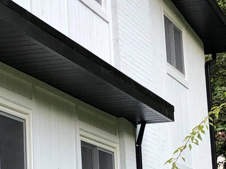 A white house with a black gutter and a black roof.