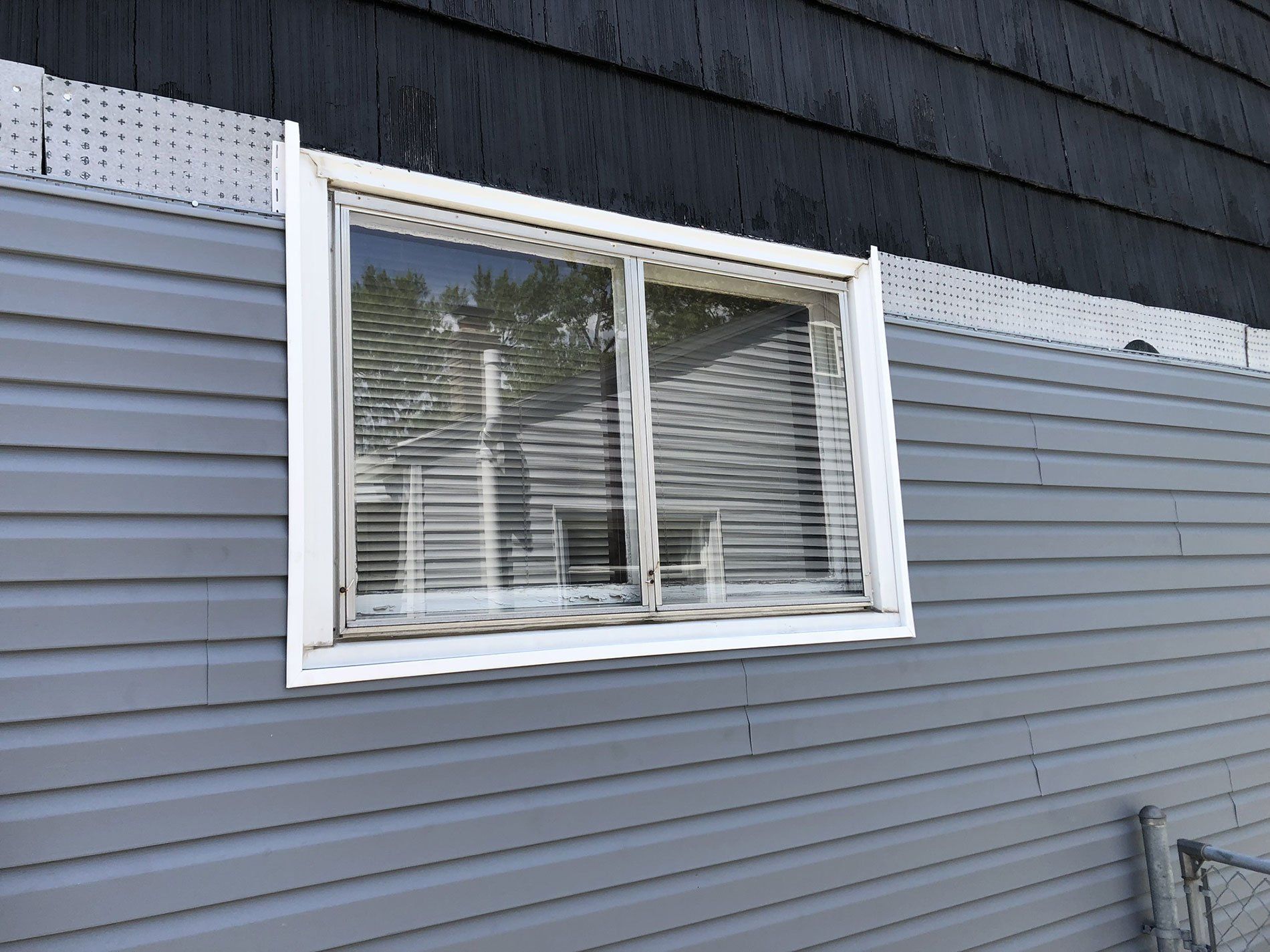 A window on the side of a house with blinds.