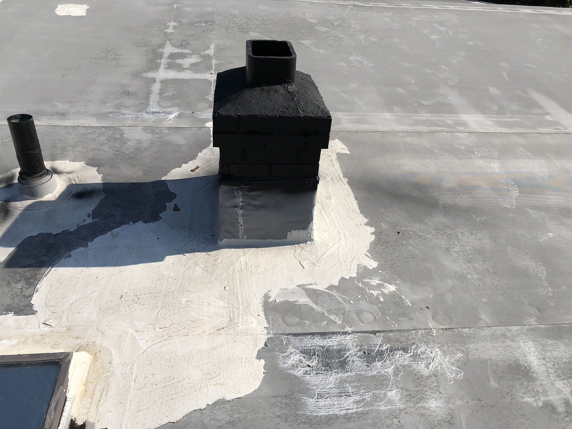 A chimney is sitting on top of a concrete roof.