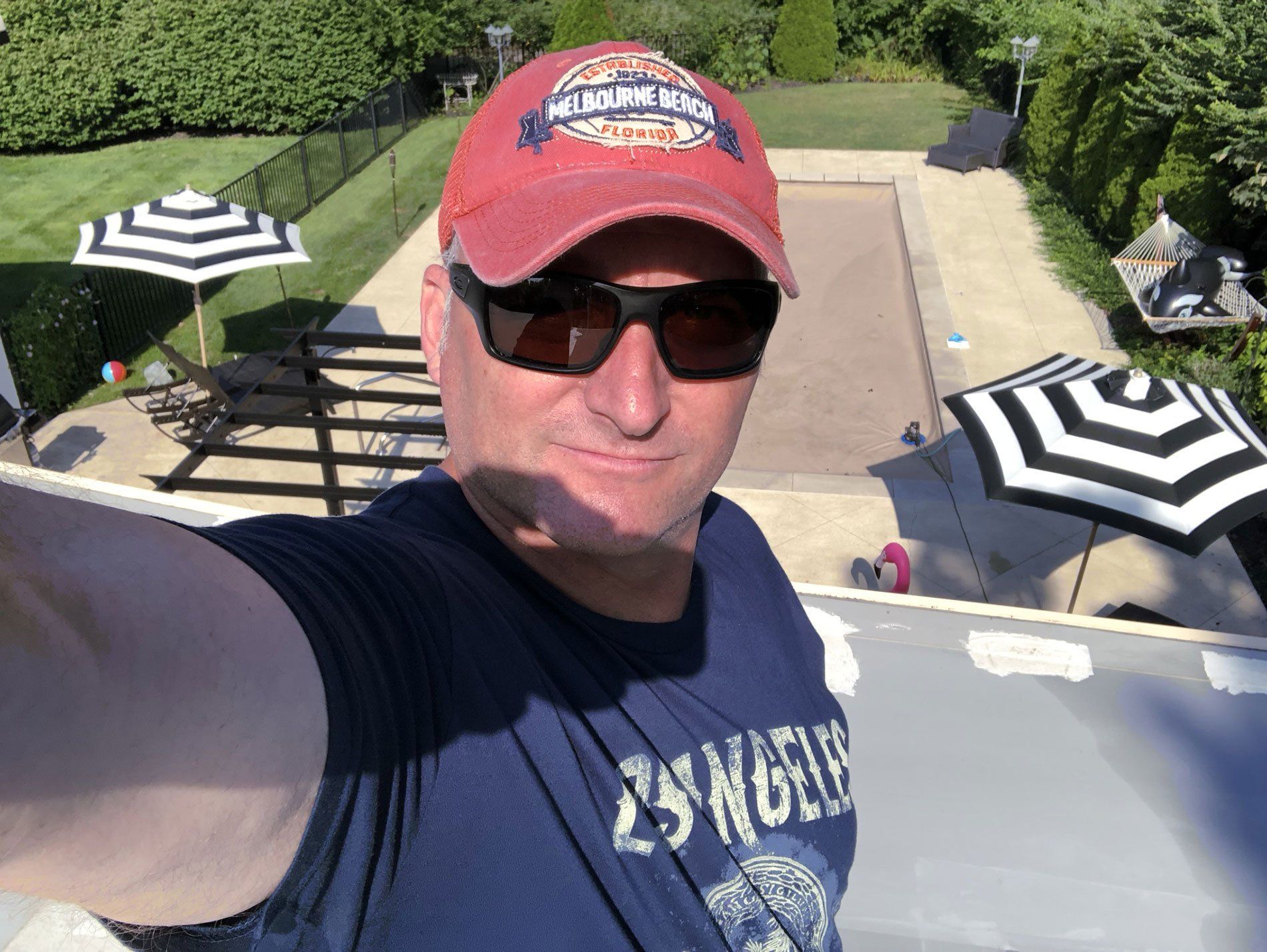 A man wearing a red hat and sunglasses is taking a selfie