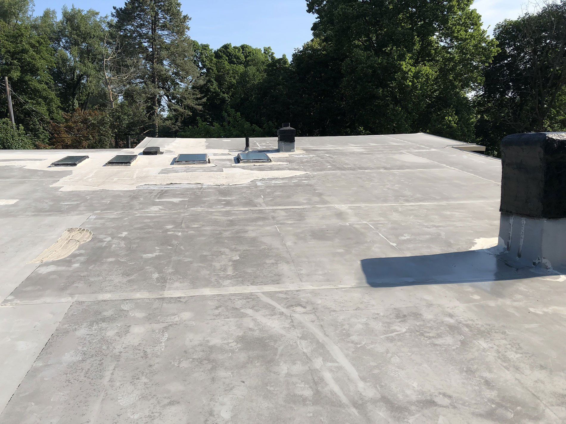 A roof with a chimney on it and trees in the background.