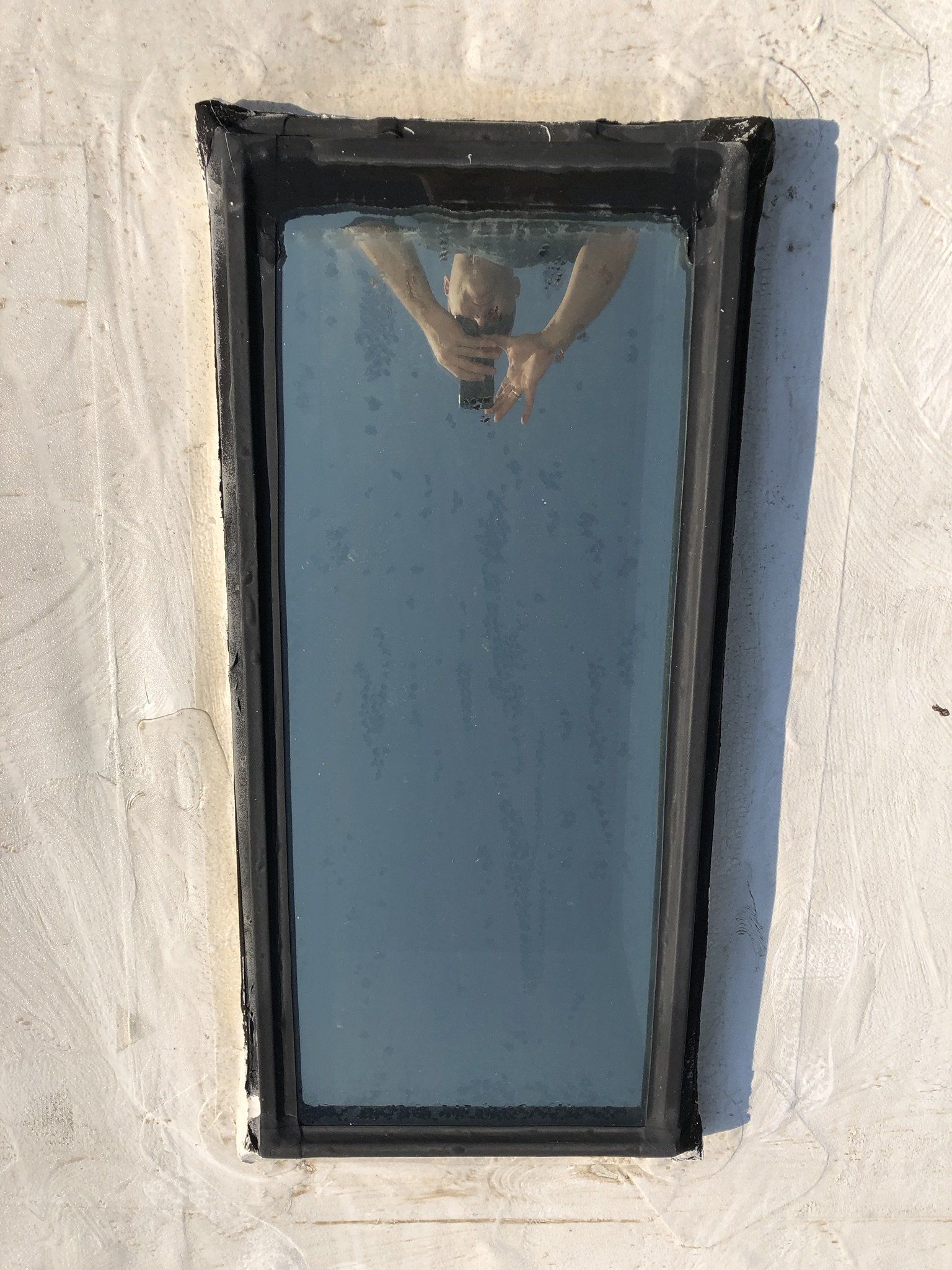 A person is reflected in a window on a building.
