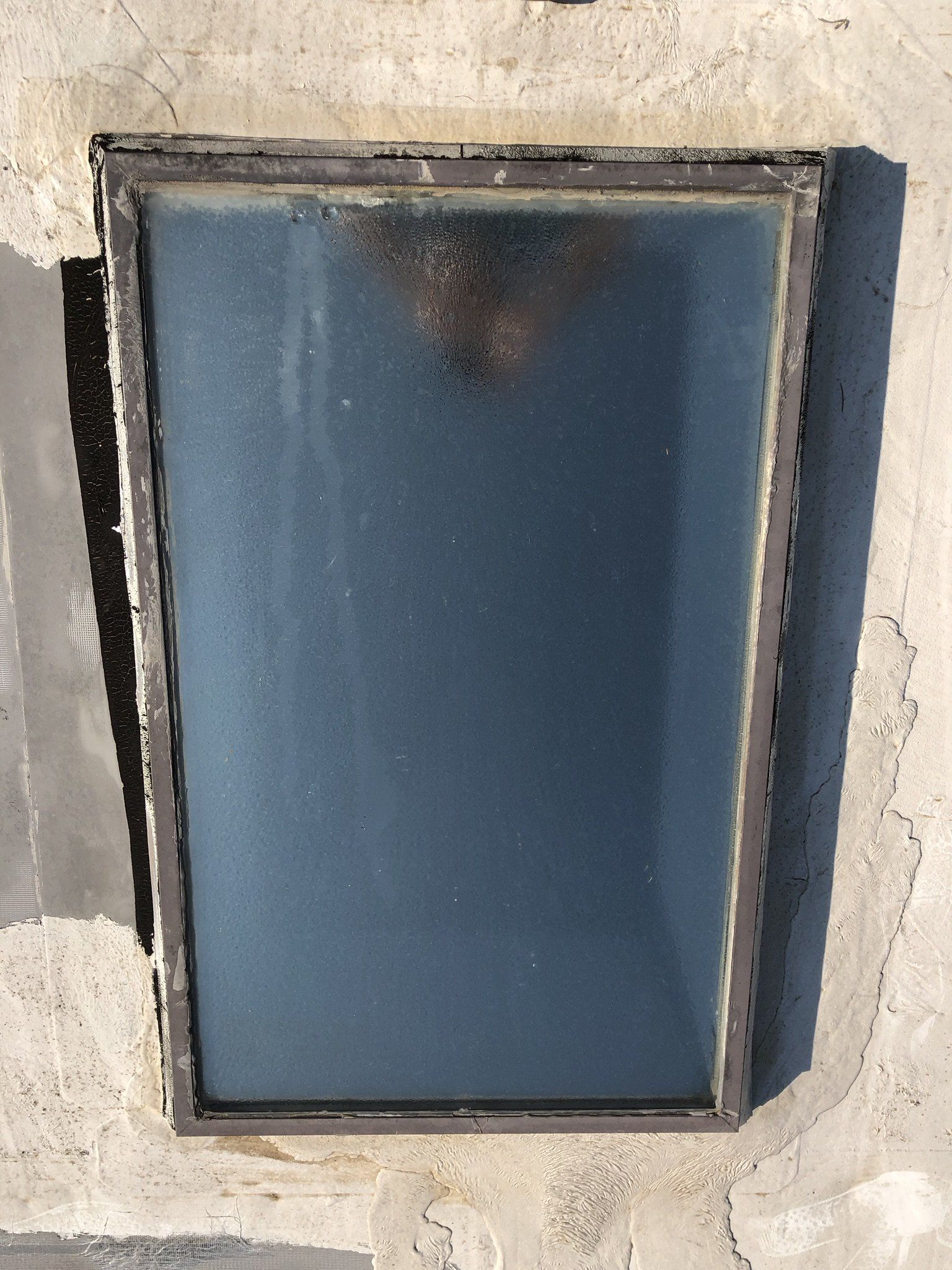 A rectangular window with a metal frame on a concrete wall