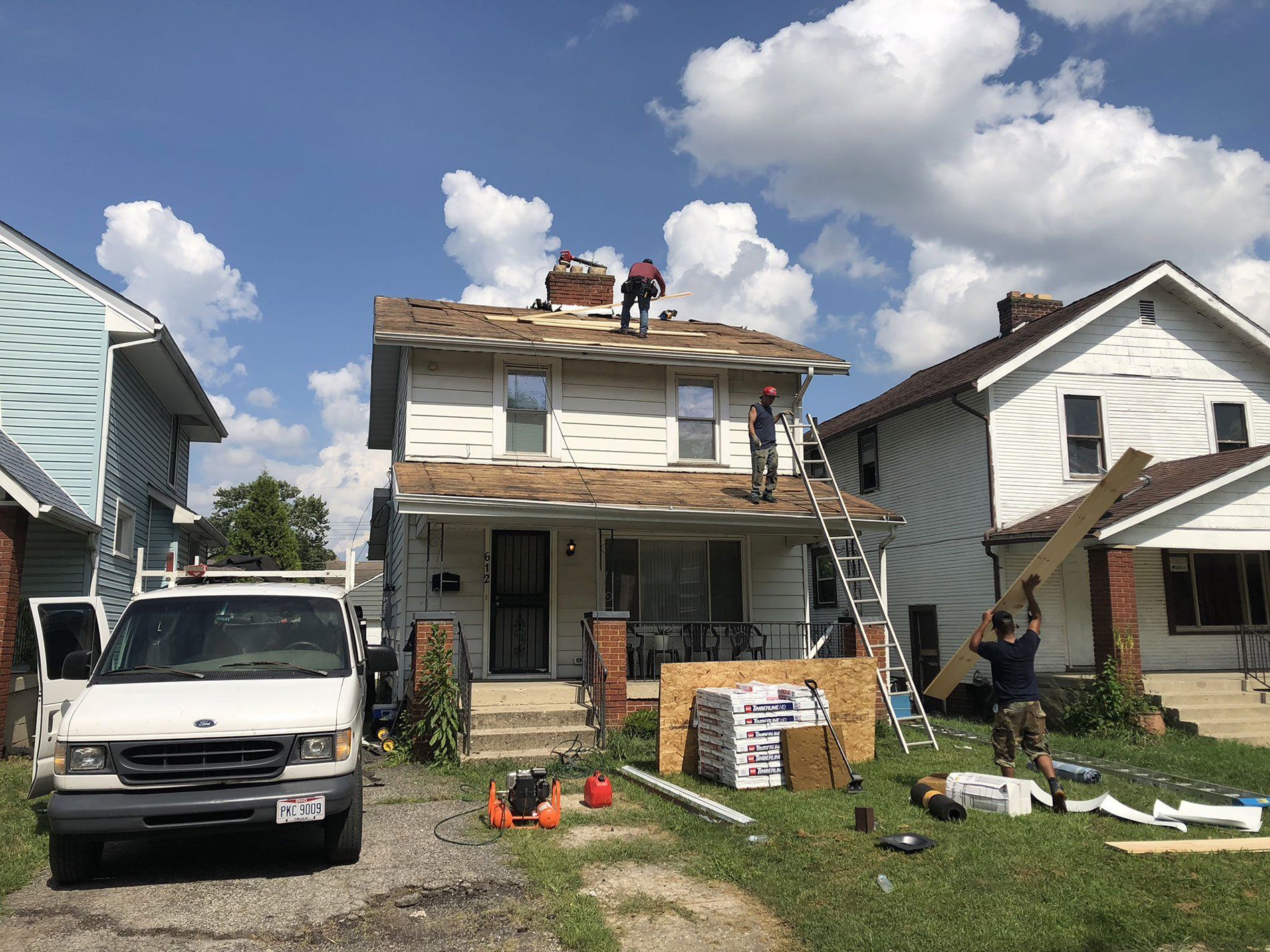 A white van is parked in front of a house that is being remodeled.