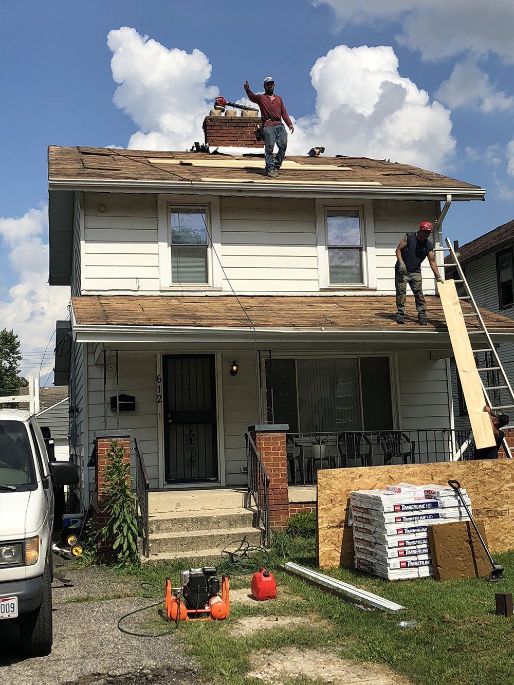 Two men are working on the roof of a house.