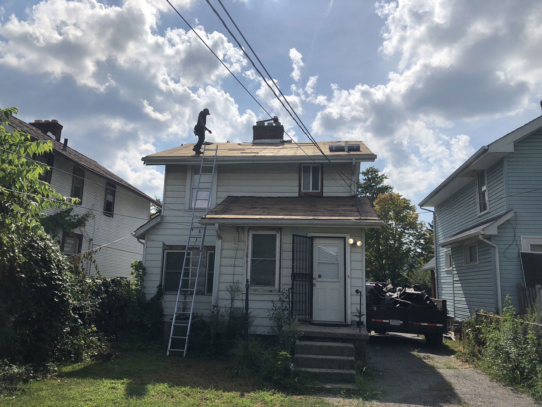 A man on a ladder is working on the roof of a house.