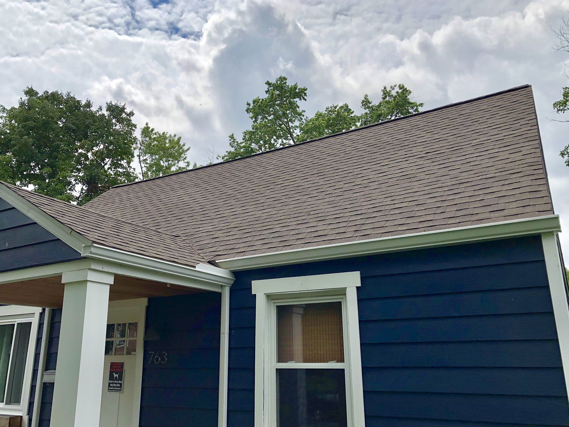 A blue house with a brown roof and white trim