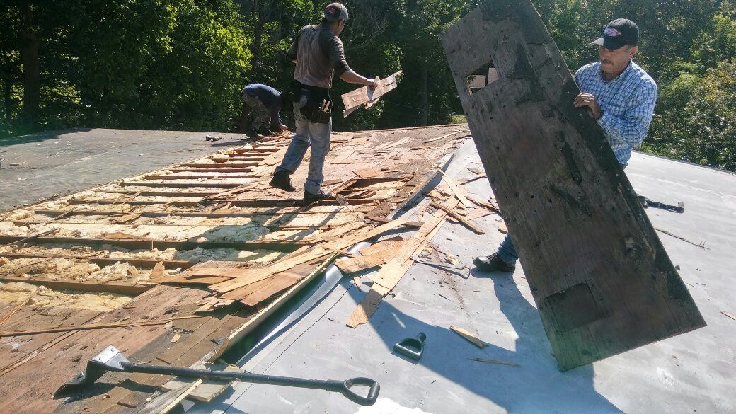 A man is carrying a large piece of wood on a roof.