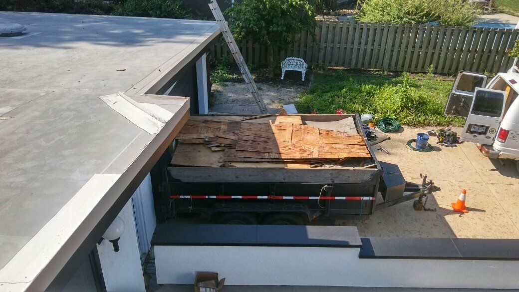 The roof of a house is being repaired and a truck is parked on the side of the road.