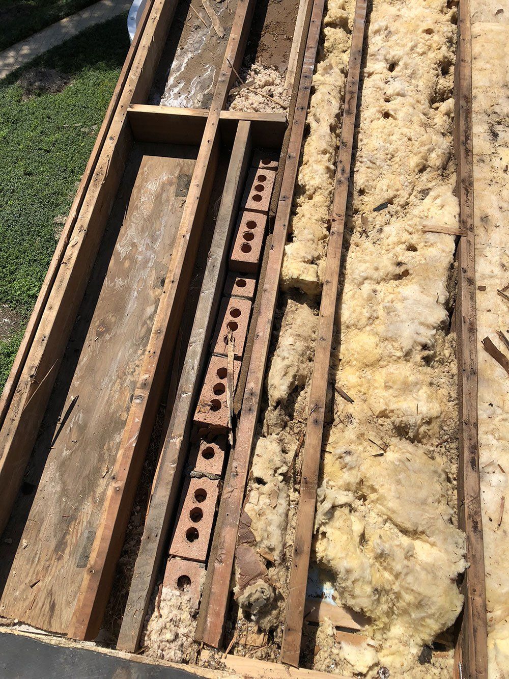 A wooden box with bricks in it is sitting on top of a pile of rocks.