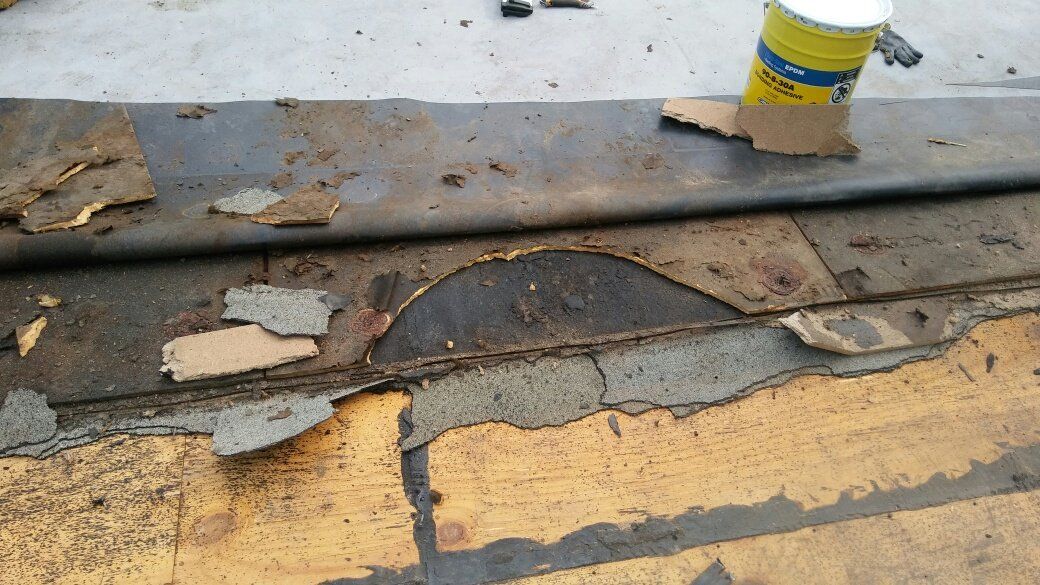 A roof with a hole in it and a can of paint on the ground.