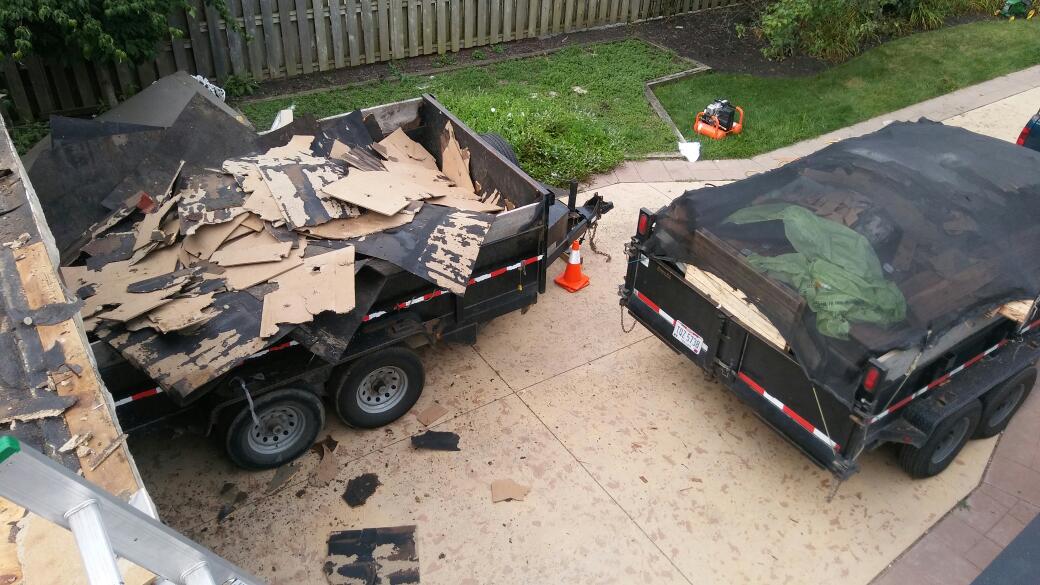 A trailer with a lot of shingles on it is parked in a driveway.