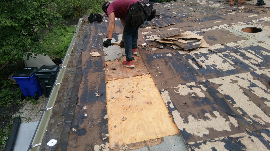 A man is working on a roof with a hammer.