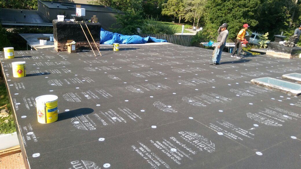 A man is standing on a roof with buckets of paint.