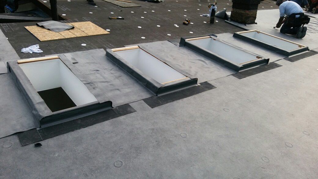 A row of skylights are being installed on a roof