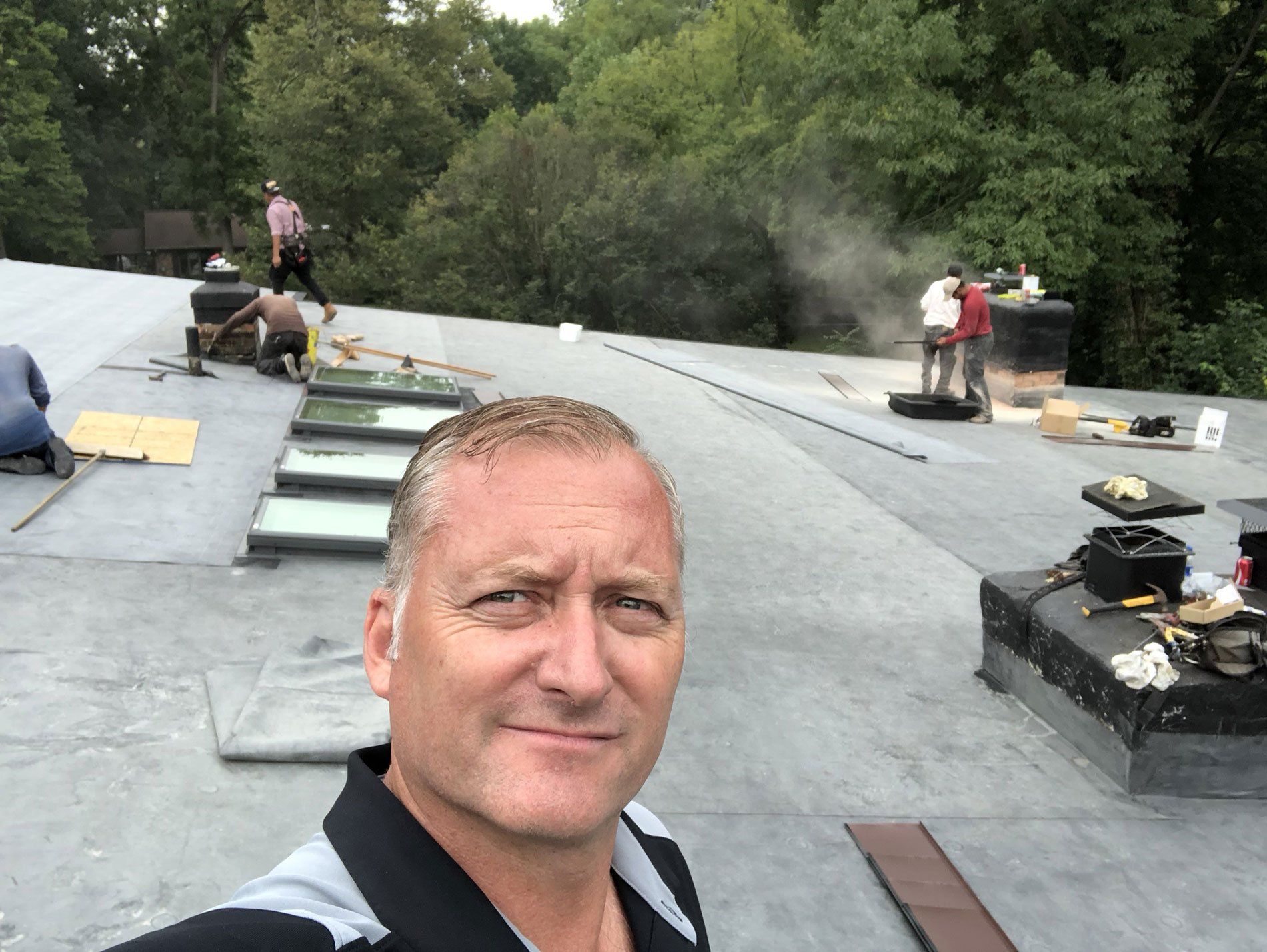 A man is taking a selfie on the roof of a building.
