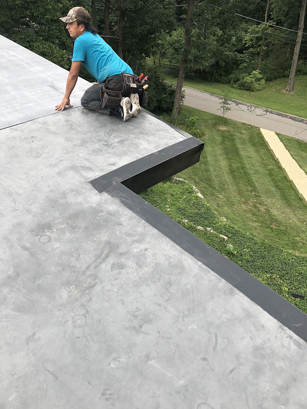 A man is kneeling on top of a concrete roof.