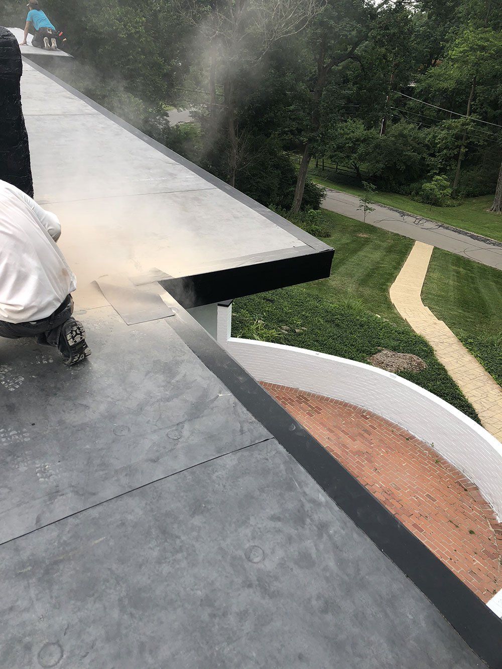 A person is spraying a roof with a hose.