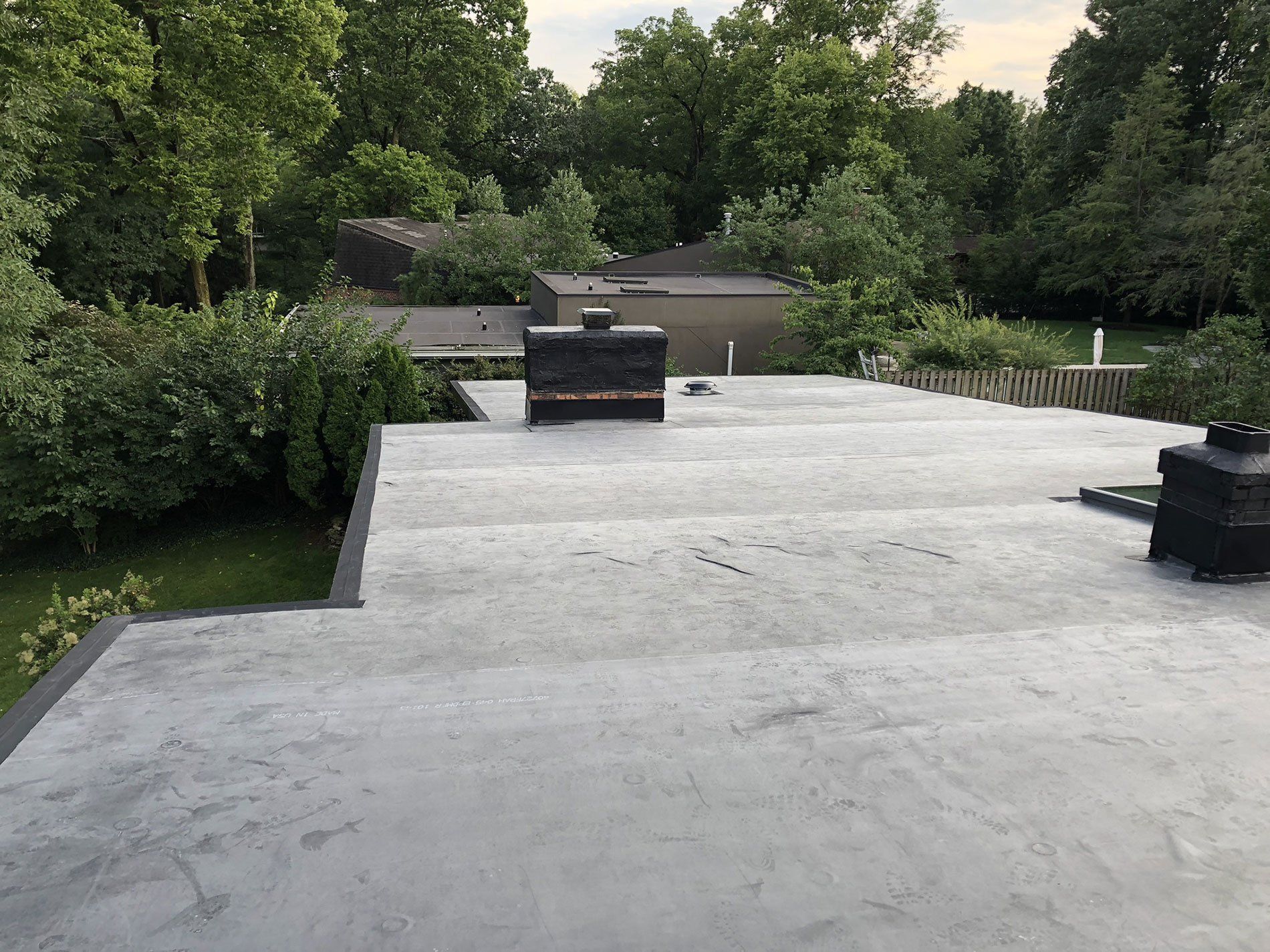A roof with a chimney on it and trees in the background.