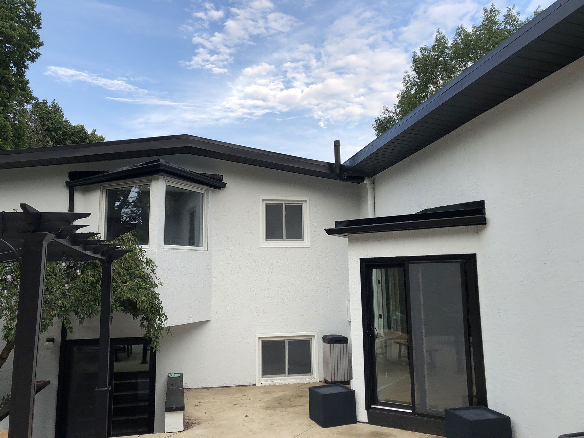 A white house with a black roof and sliding glass doors