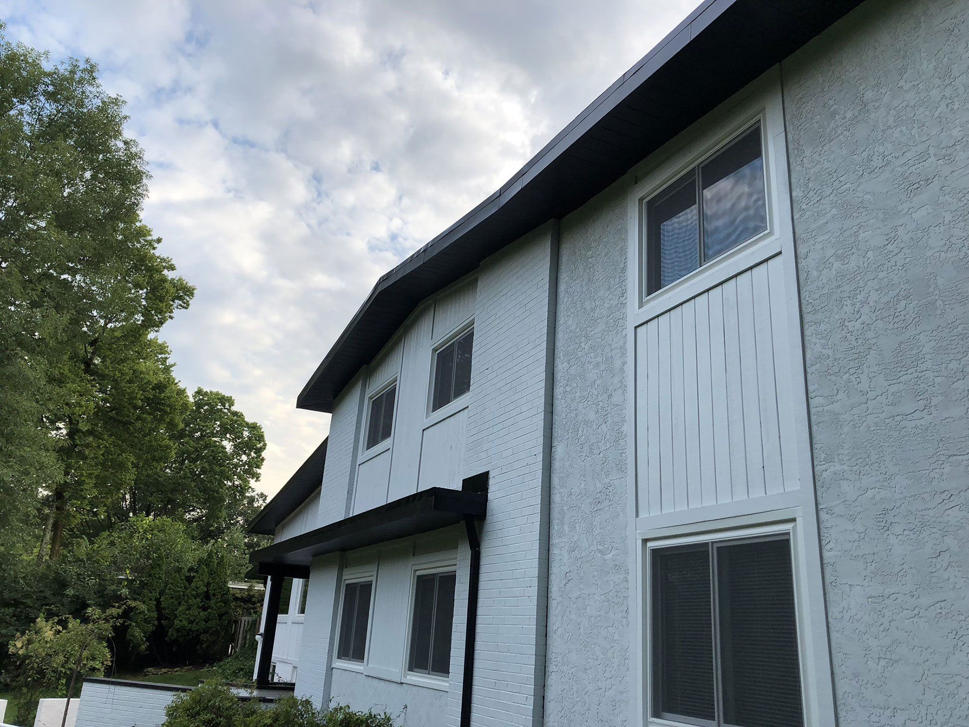 A white house with a black roof and a lot of windows