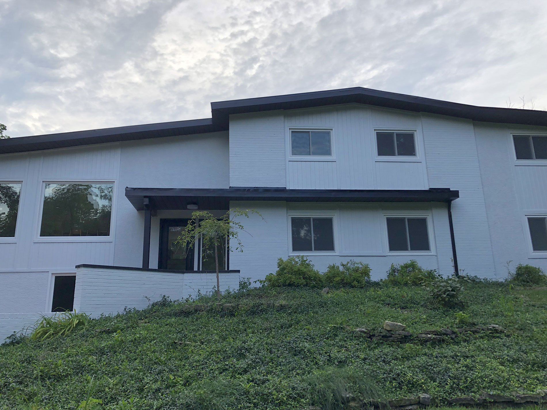 A large white house is sitting on top of a grassy hill.