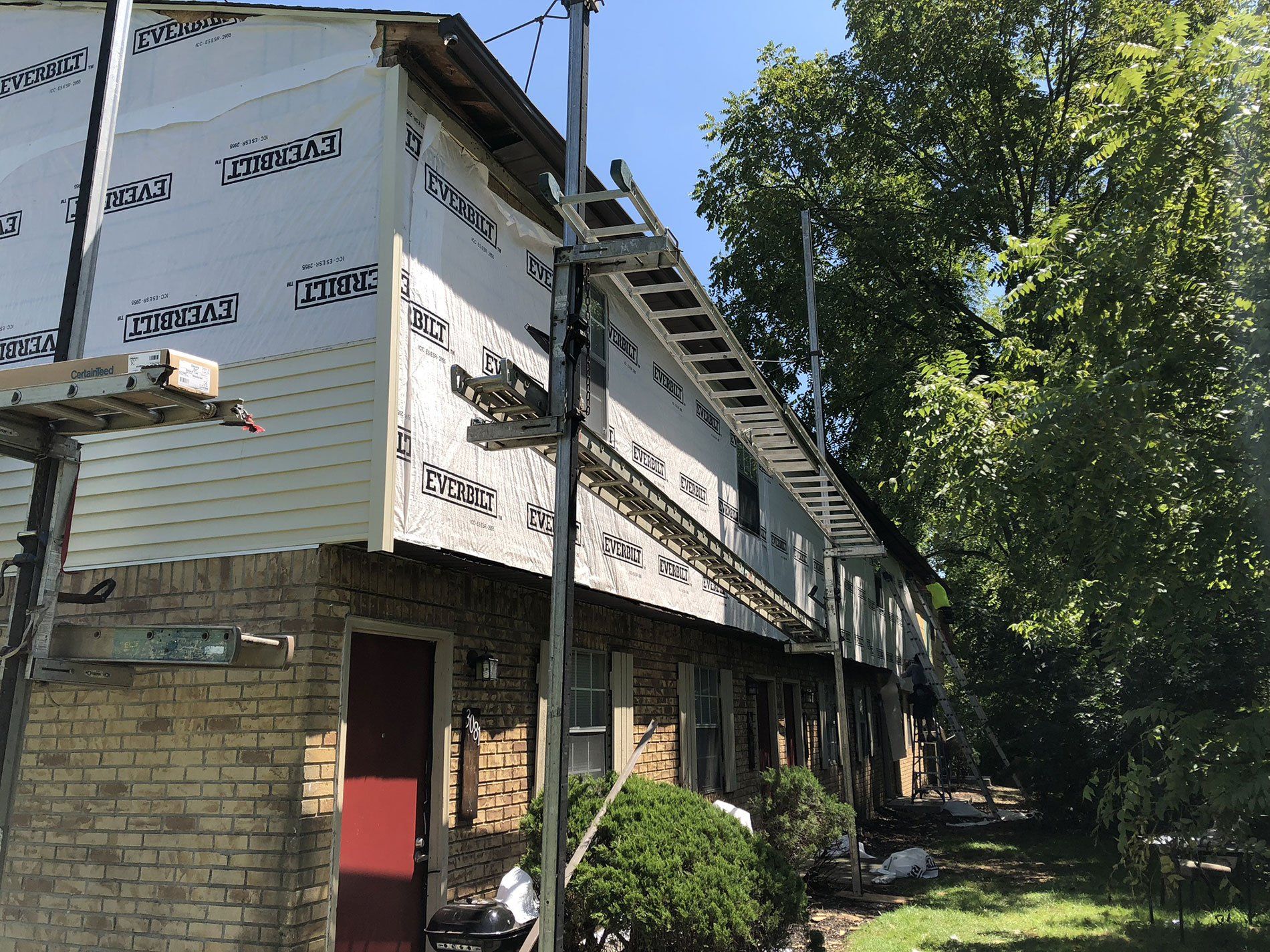 A brick building with siding being installed on it.