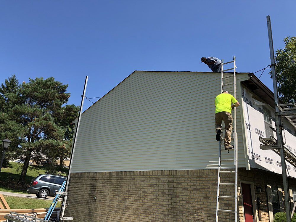 Two men are working on the roof of a house.