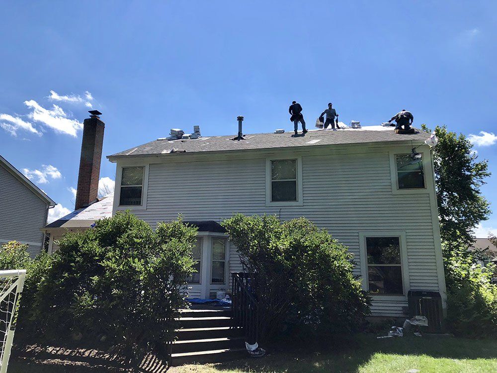 A group of people are working on the roof of a house.