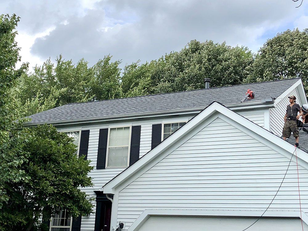 Two men are working on the roof of a house.