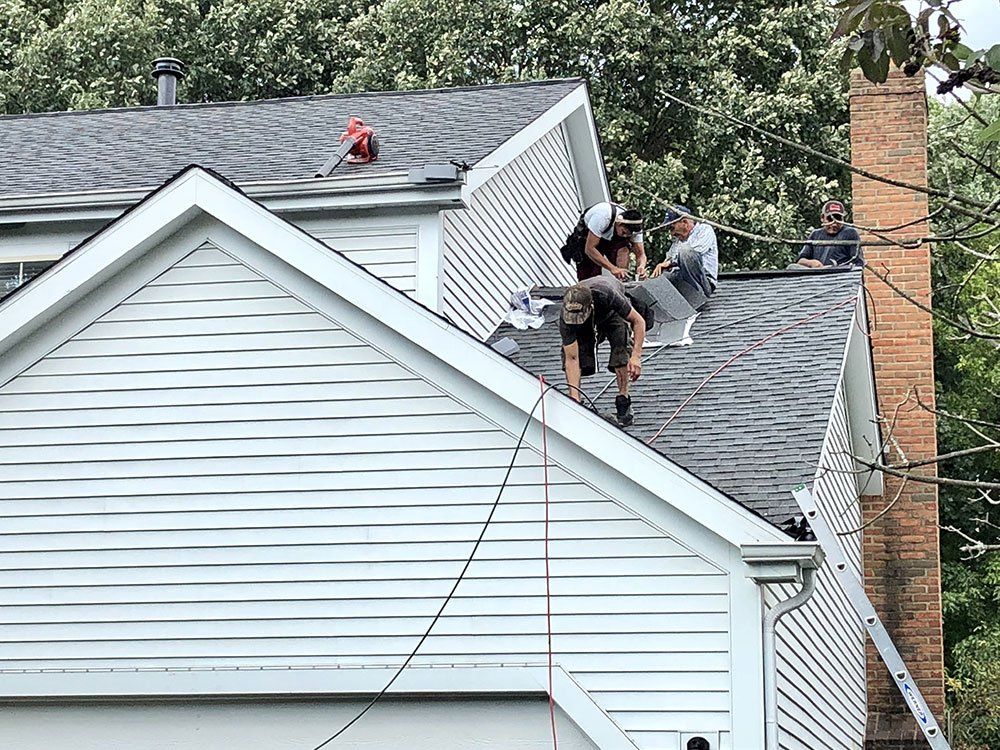 A group of men are working on the roof of a house.