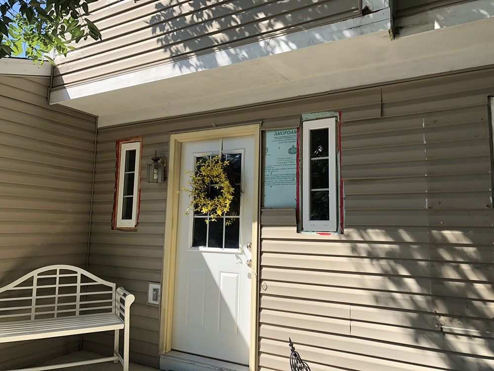 The front door of a house with a wreath on it and a bench.