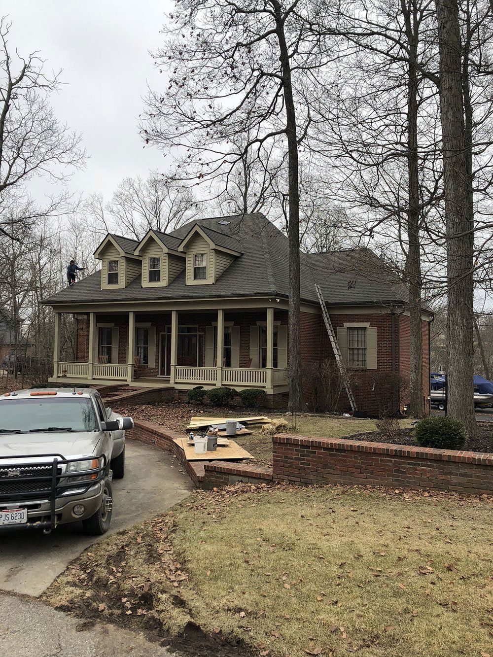 A large brick house with a porch and a truck parked in front of it.