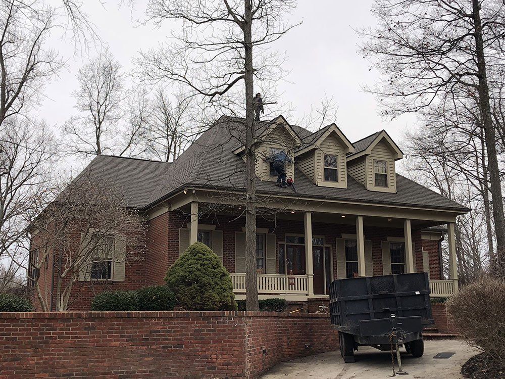 A man is working on the roof of a large brick house.