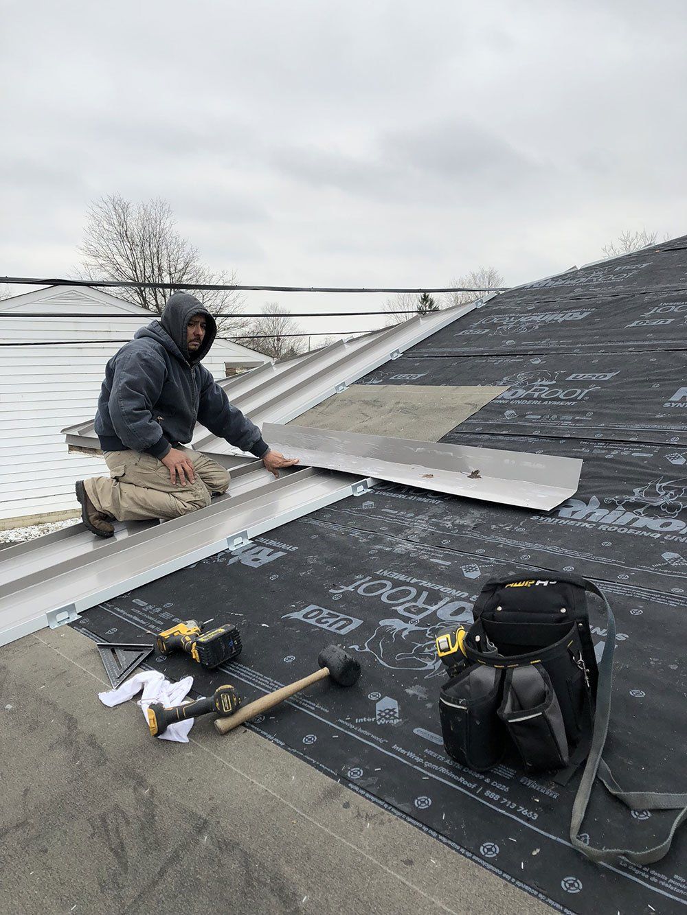 A man is kneeling on the roof of a building.