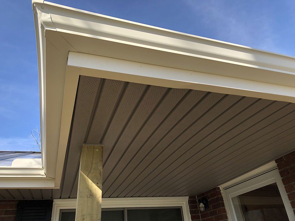 The roof of a house with a white gutter and a blue sky in the background.