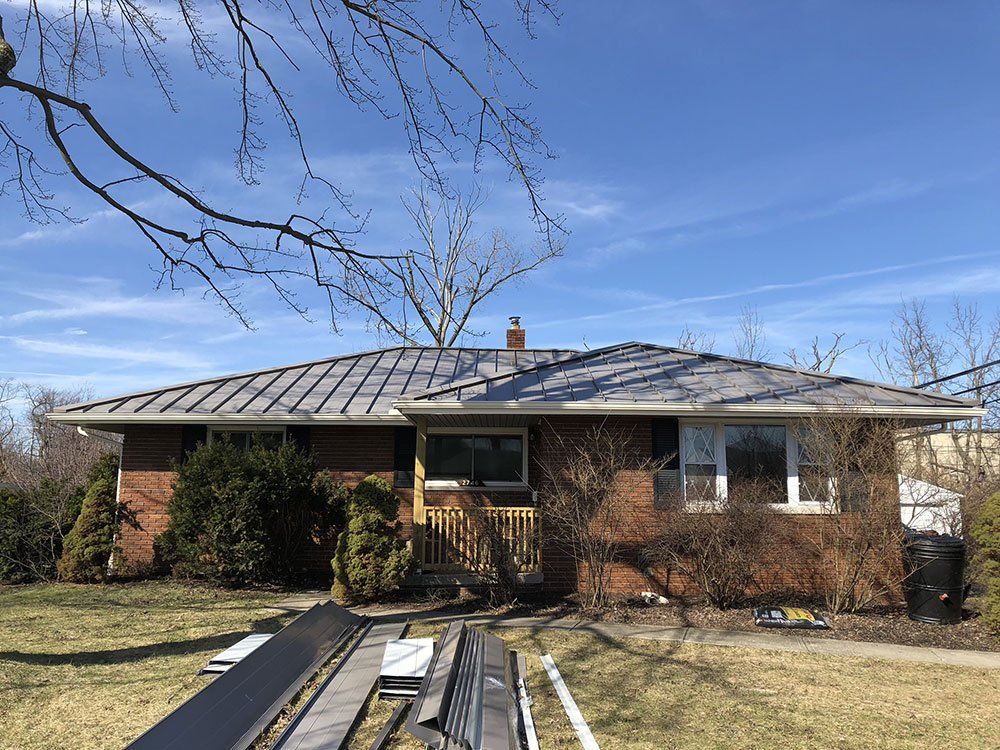 A brick house with a metal roof is being remodeled.