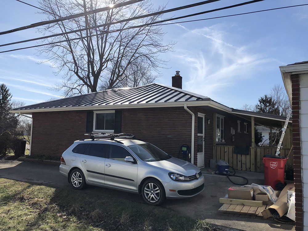 A silver car is parked in front of a brick house.