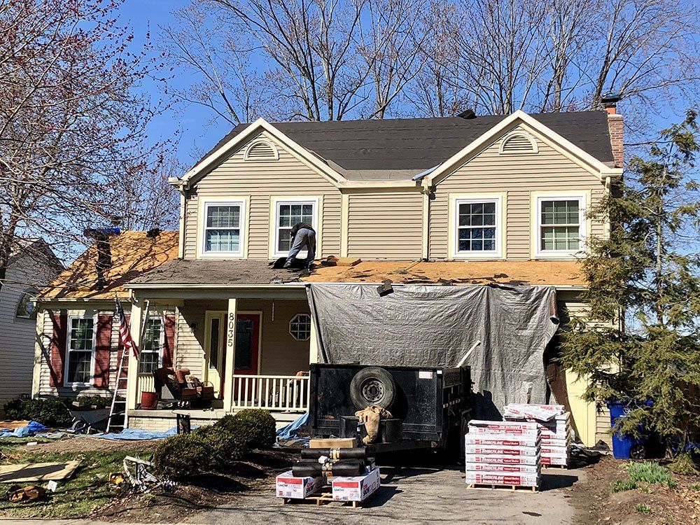 A house with a roof being installed and a truck parked in front of it.
