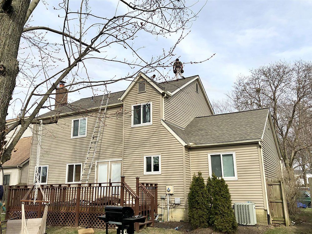 A man is standing on the roof of a house.
