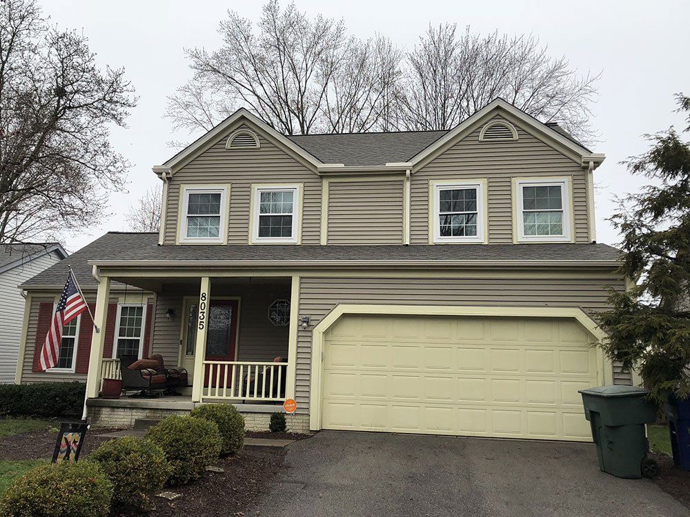 A large house with a yellow garage door and a porch.