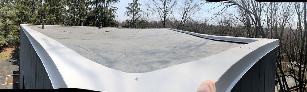 A person is holding a piece of paper on top of a roof.