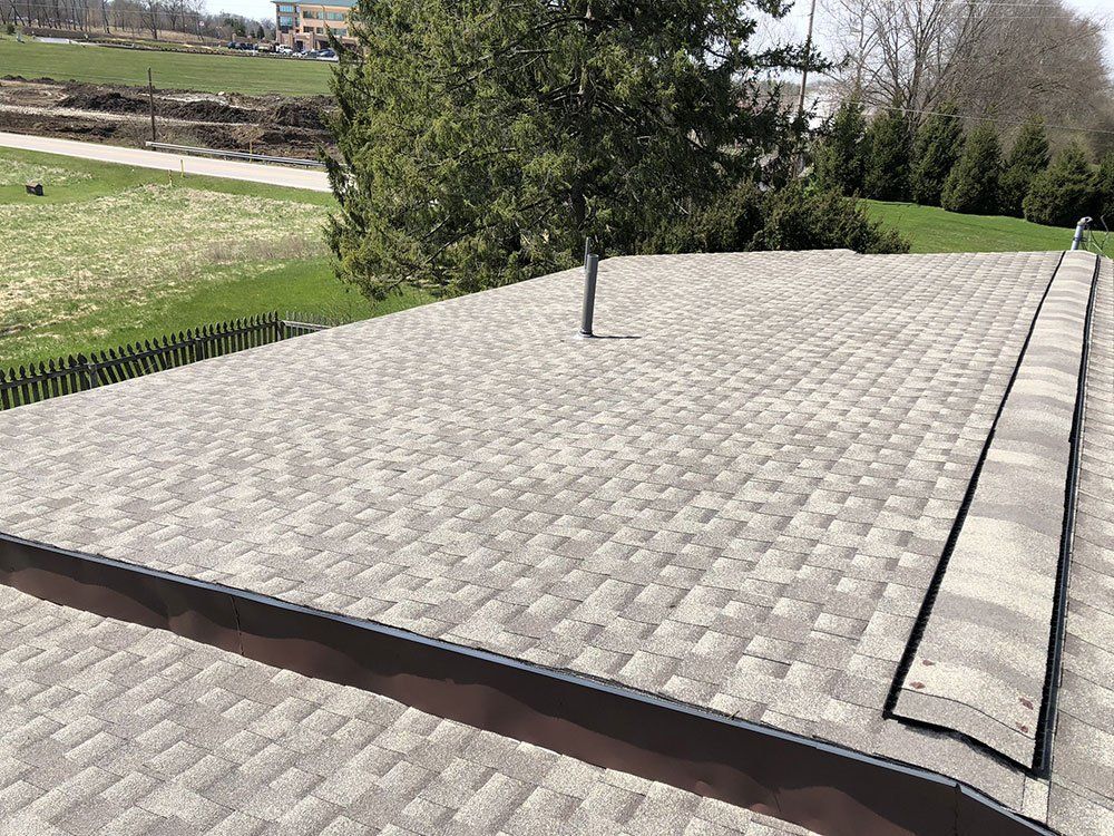 A roof with a tree in the background and a fence around it.