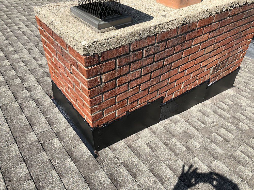 A brick chimney is sitting on top of a roof.
