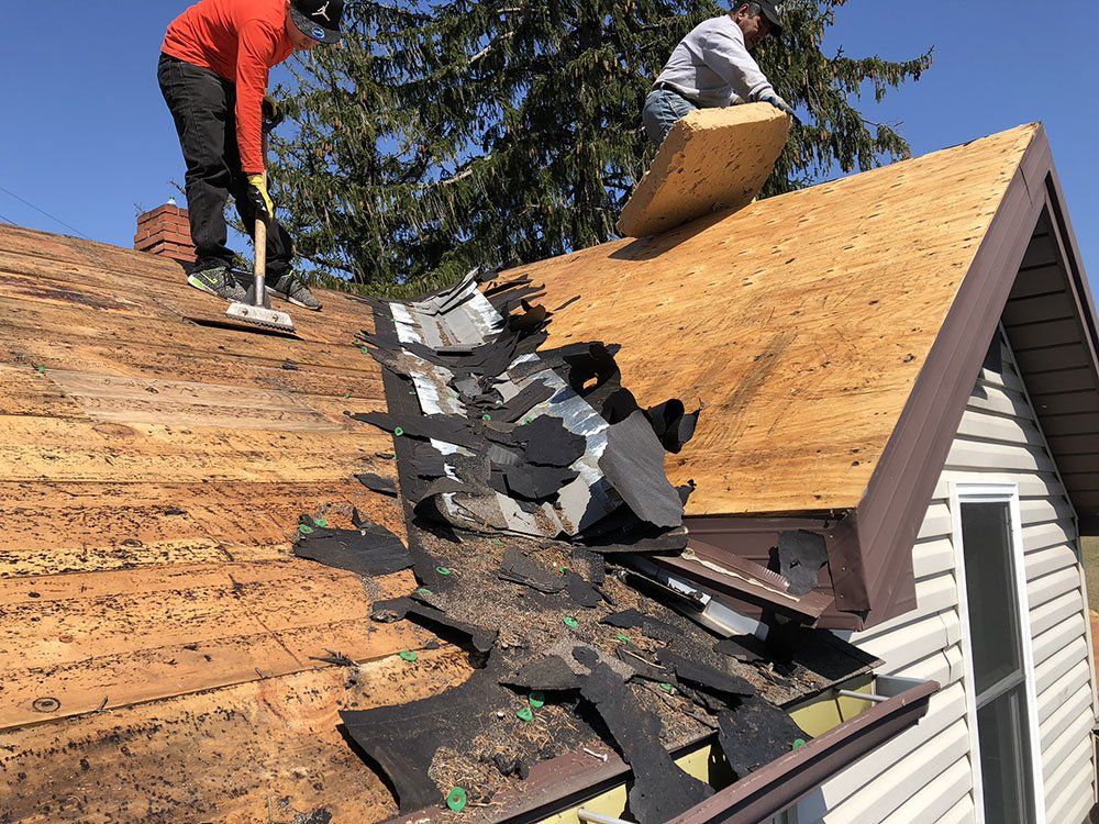 Two men are working on the roof of a house.