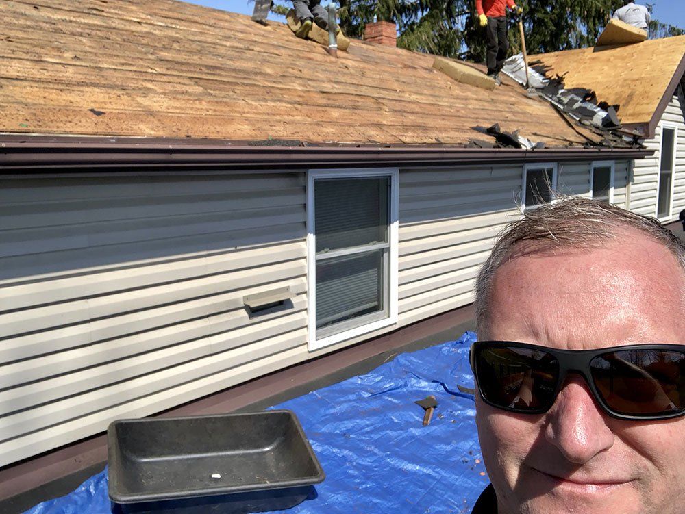 A man wearing sunglasses is standing in front of a house under construction.